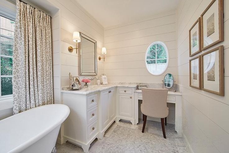 White bathroom with freestanding tub, marble countertop vanity, built-in makeup desk, and soft neutral decor.