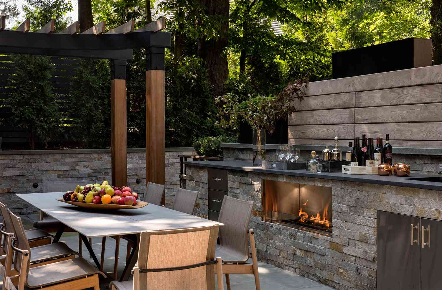 Modern outdoor kitchen and dining area with fireplace 
