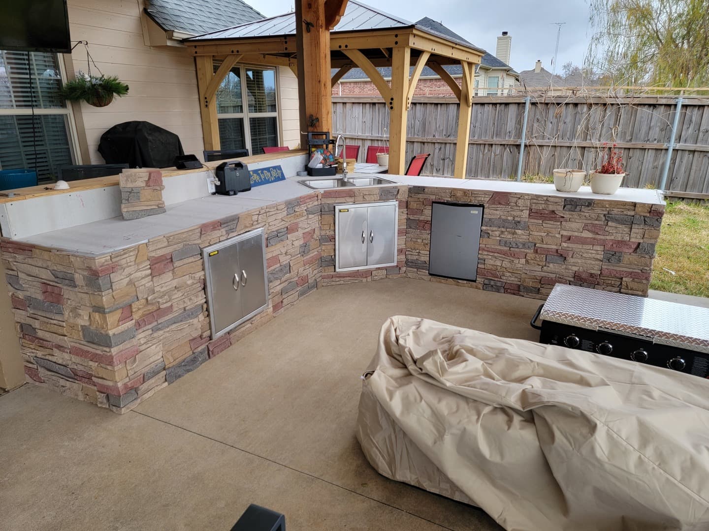 DIY outdoor kitchen with stone veneer and stainless steel appliances