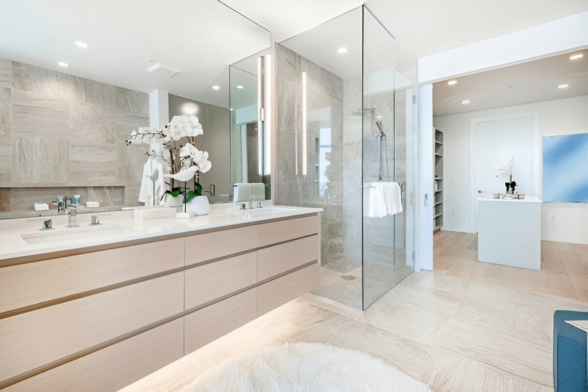Spacious modern bathroom with floating double vanity, glass shower, and natural stone finishes.