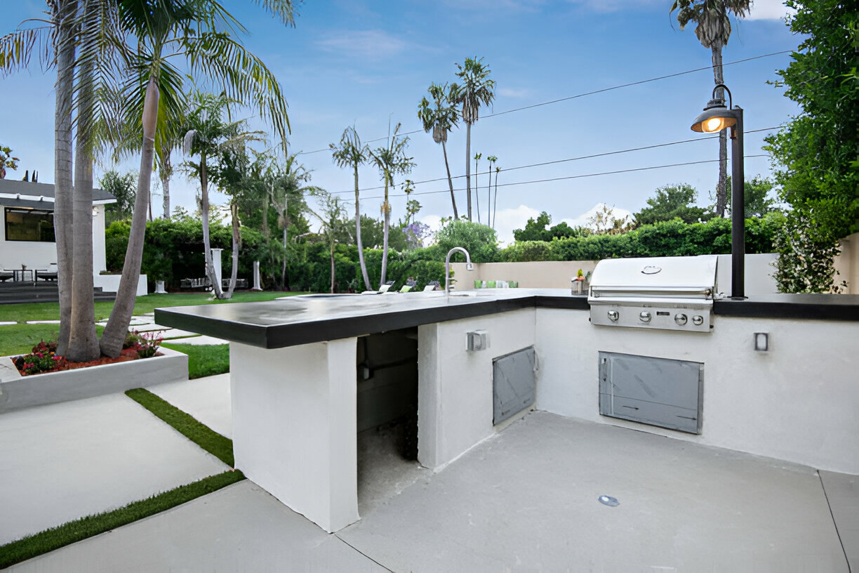 Modern outdoor kitchen with grill and sink in a tropical backyard 