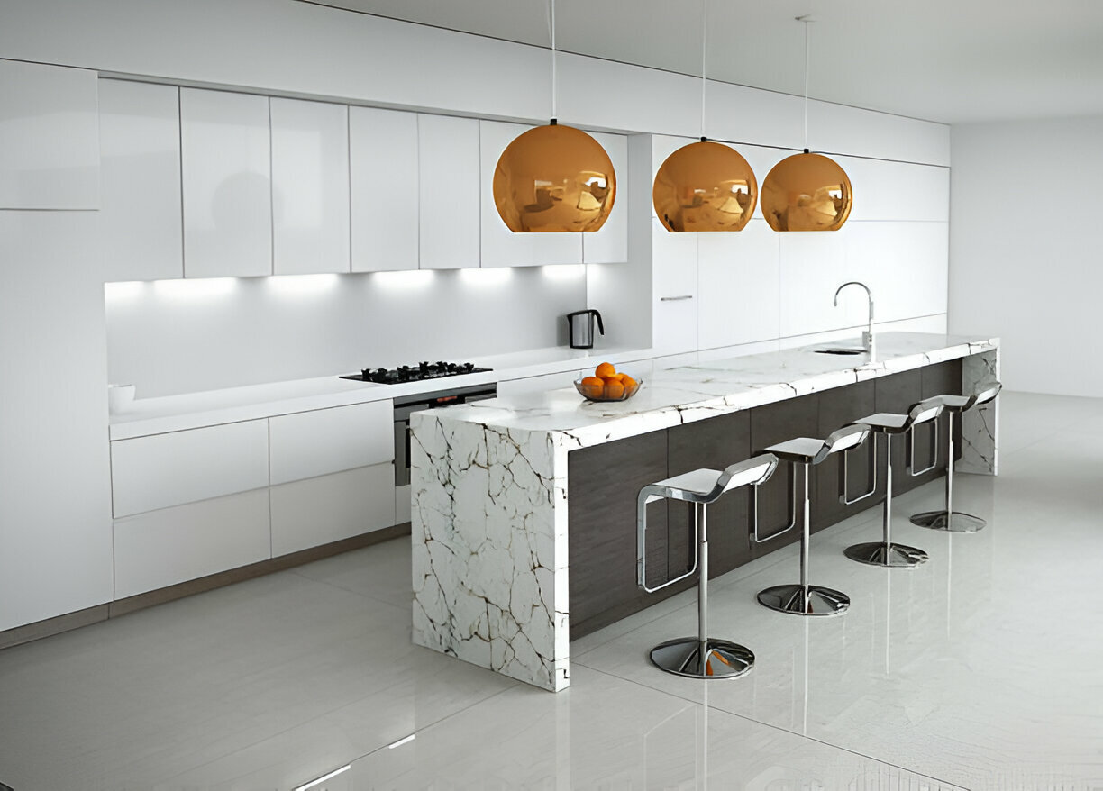 Sleek modern kitchen featuring a long marble island and orange pendant lights 