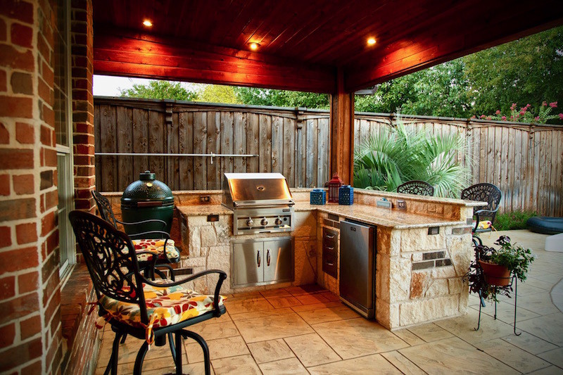 Covered outdoor kitchen with stone countertops and Kamado grill