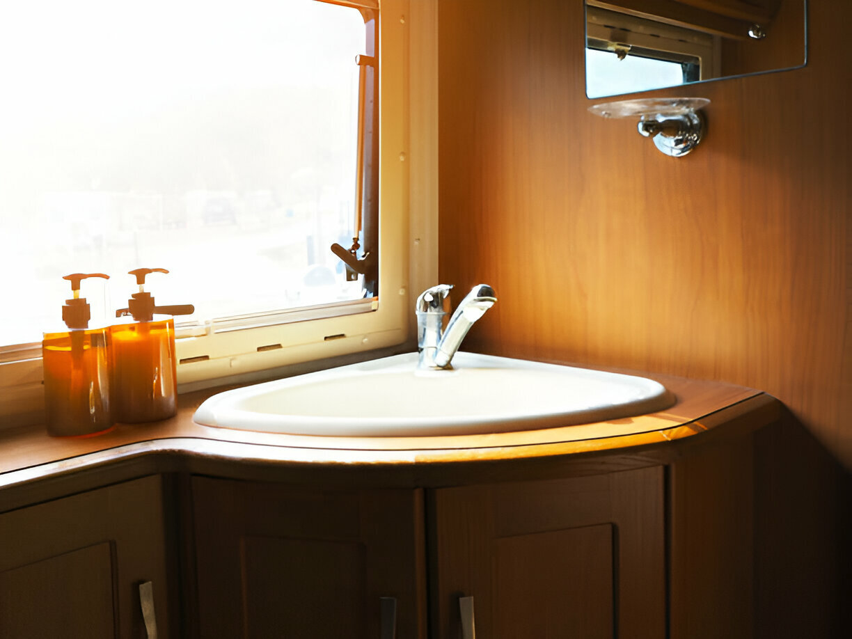 Small corner sink in a wooden vanity next to a window