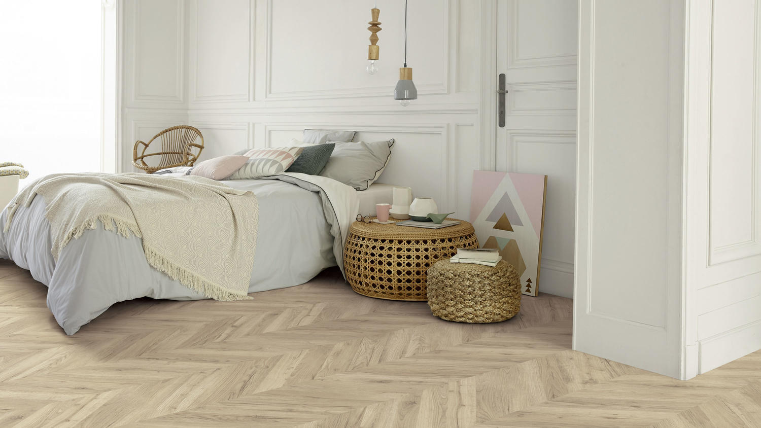 Minimalist bedroom with beige herringbone laminate flooring, low bed, wicker furniture, and white wall paneling