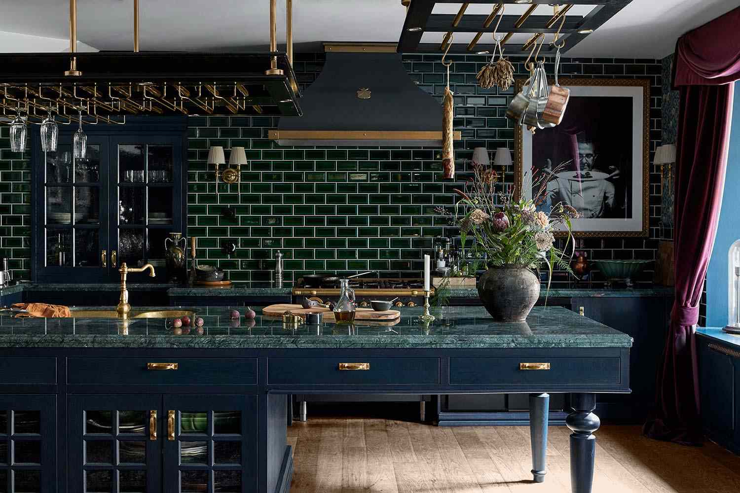 Luxurious kitchen featuring emerald green subway tile backsplash, dark blue cabinetry, brass fixtures, and green marble countertop