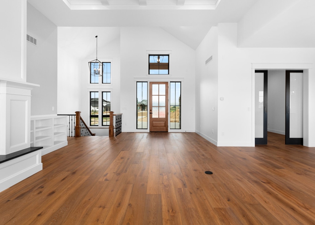 Modern entryway with natural oak wide-plank hardwood flooring, vaulted ceiling, and large windows with black trim