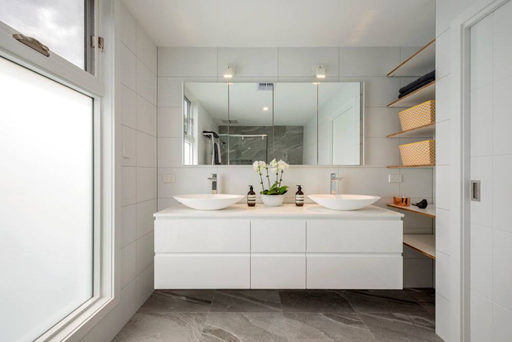 Contemporary bathroom with white floating double vanity, vessel sinks, and built-in wooden shelves