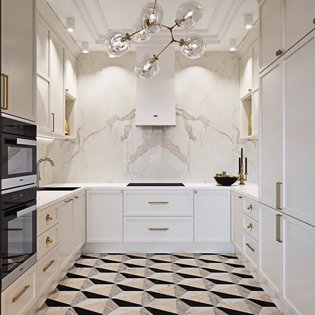 Luxurious white U-shaped kitchen with gold hardware, marble backsplash, and bold geometric floor tiles