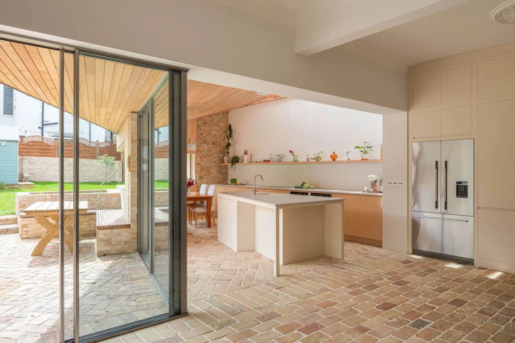 Modern kitchen with exposed brick flooring and sliding glass doors opening to an outdoor patio.