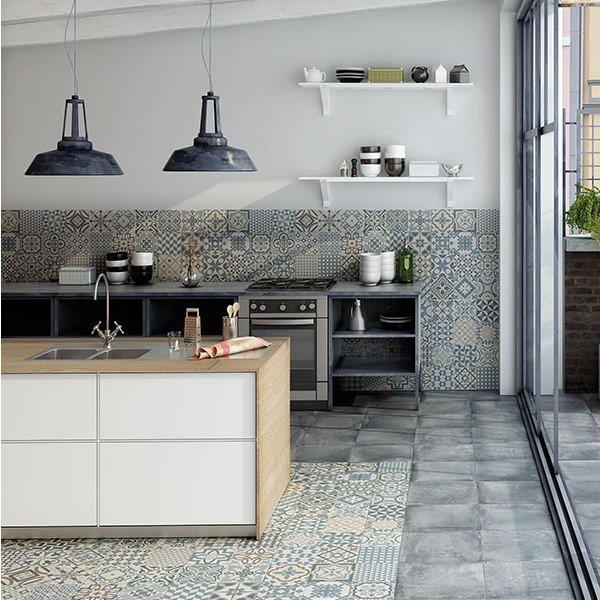 Modern industrial kitchen featuring decorative blue-grey backsplash and patterned tile inlay under the island, combined with grey concrete floor tiles.