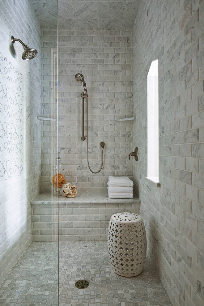 Luxurious walk-in shower with marble subway tile walls, built-in bench, hand shower, and a decorative white ceramic stool