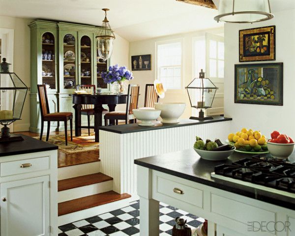 Traditional kitchen with black and white checkered flooring, white cabinetry, green hutch, and elevated dining area