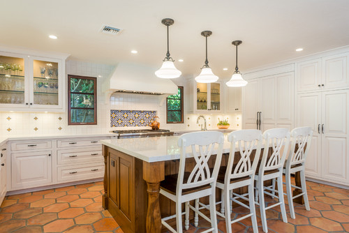 Bright kitchen featuring white cabinetry, a wood island, and terracotta hexagonal floor tiles.
