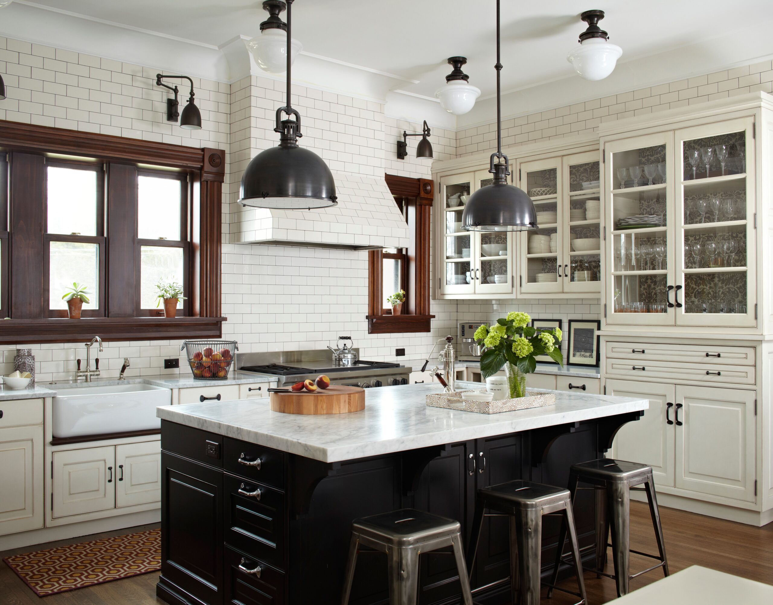 Vintage-style kitchen with white subway tile walls, cream cabinetry, and a black island with marble countertop.