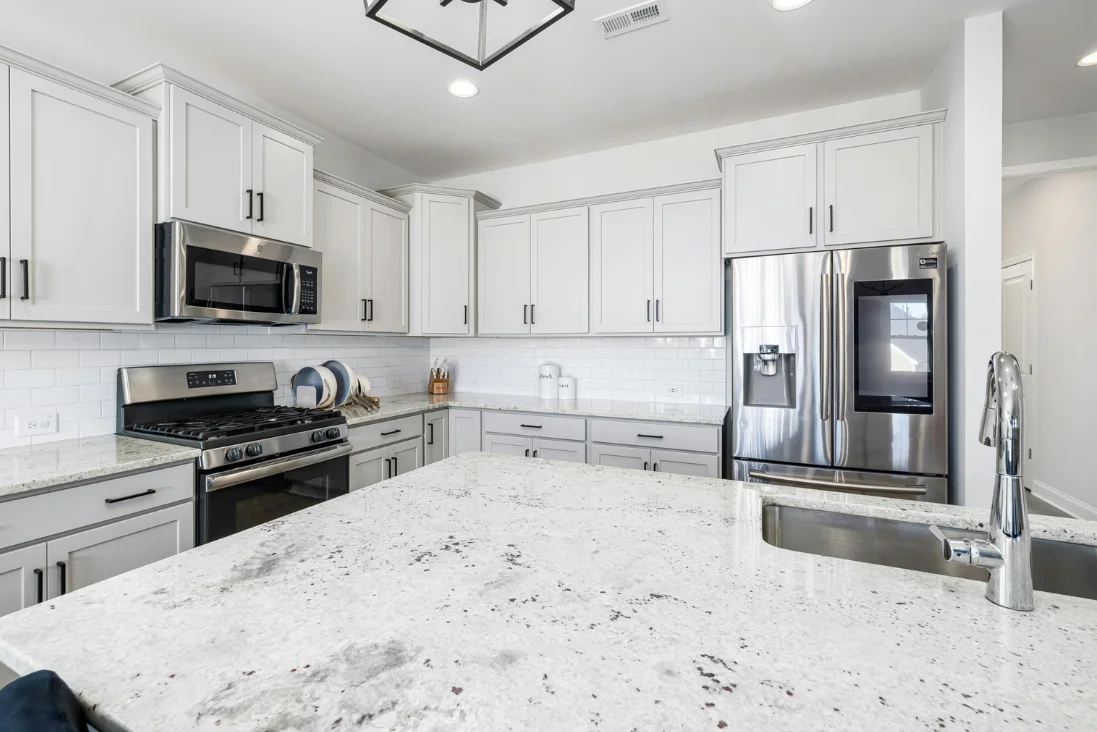 Modern kitchen with white granite countertops and stainless steel appliances