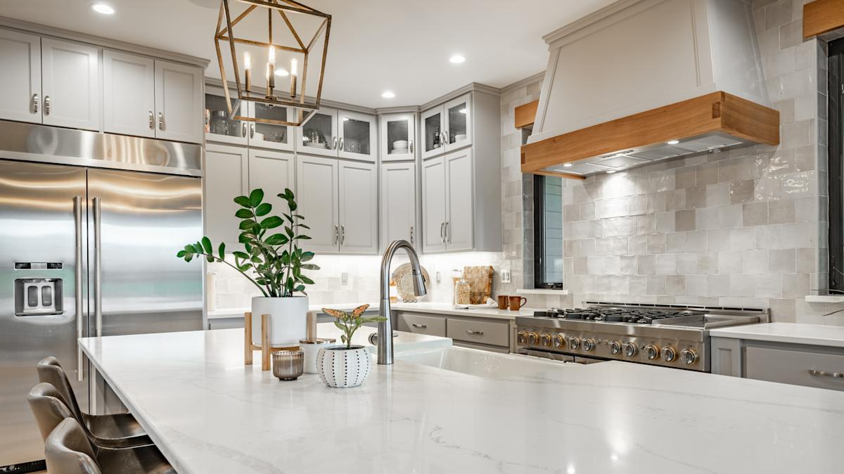 Modern kitchen with white quartz countertops, light gray cabinets, and stainless steel appliances