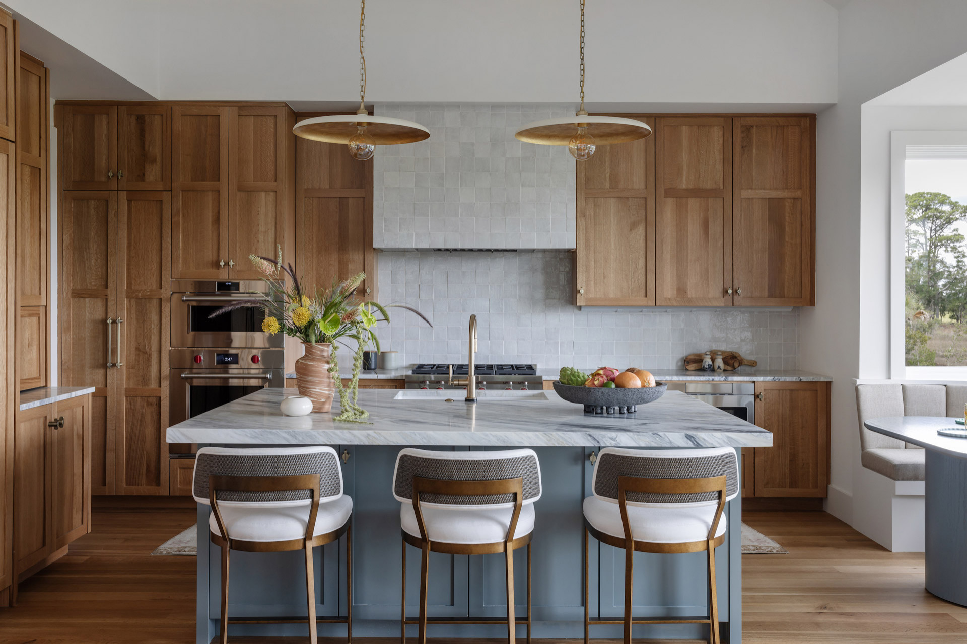 Transitional kitchen with natural wood cabinets, blue island, and marble countertops.