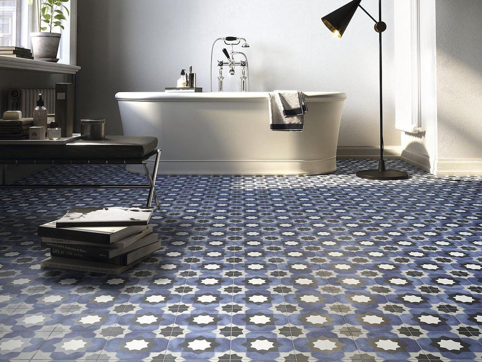 Blue patterned floor tiles in a bathroom with a freestanding white bathtub
