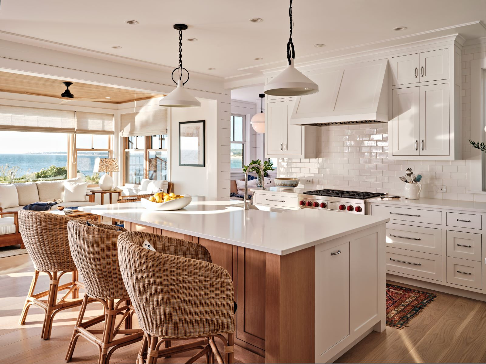 Coastal-style kitchen with white cabinetry, wicker barstools, and a view of the ocean.
