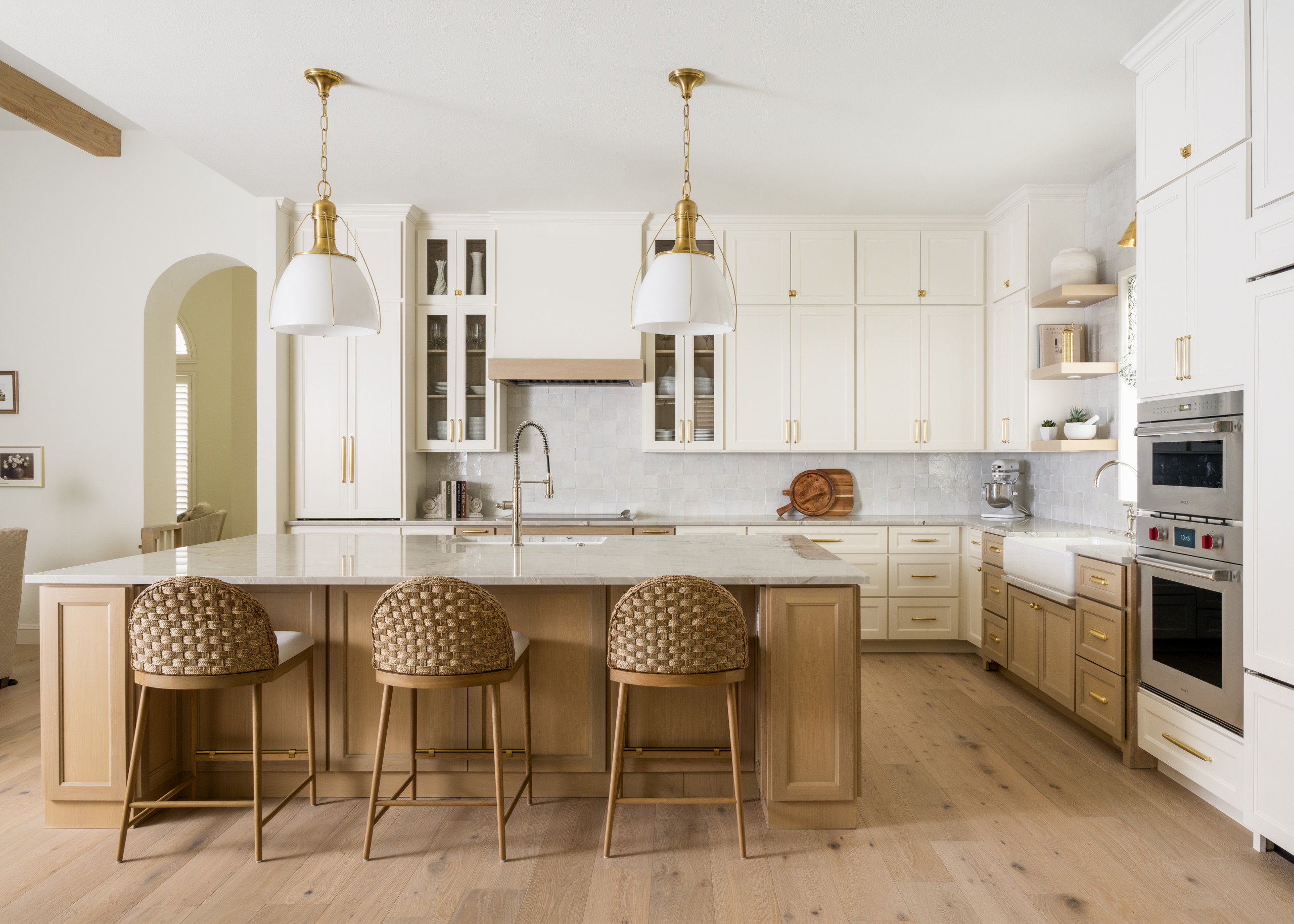 Elegant kitchen with two-tone cream and wood cabinetry, marble countertops, and gold accents.