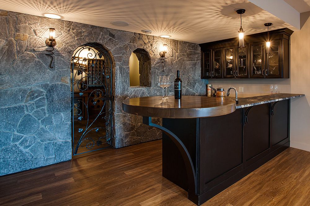 rustic home bar with stone walls, wrought iron wine cellar door, and dark wood cabinetry