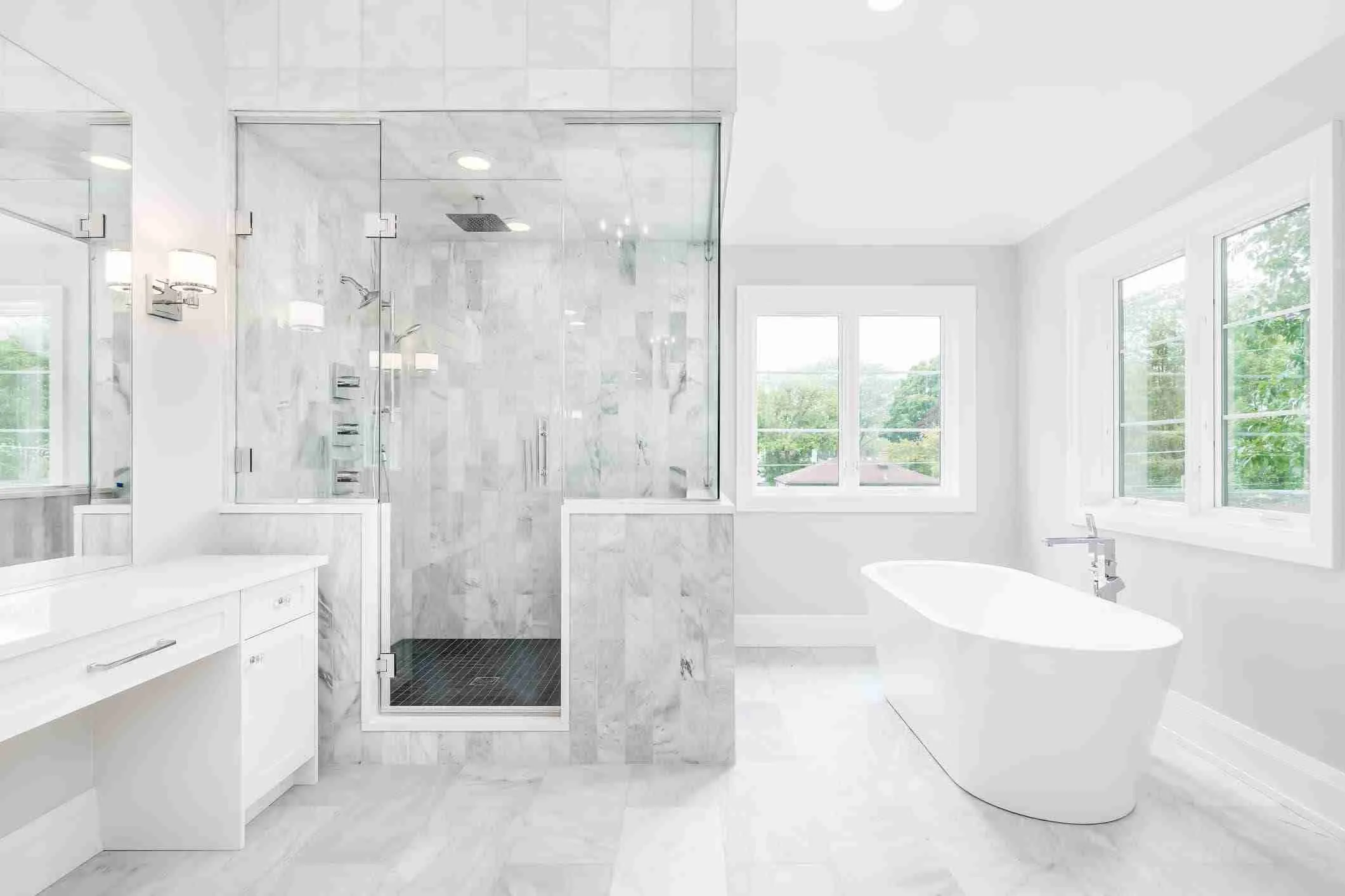 Bright white bathroom with glass shower and freestanding tub