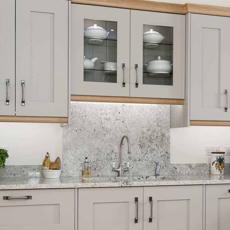 Elegant kitchen with light gray cabinets and marble granite backsplash