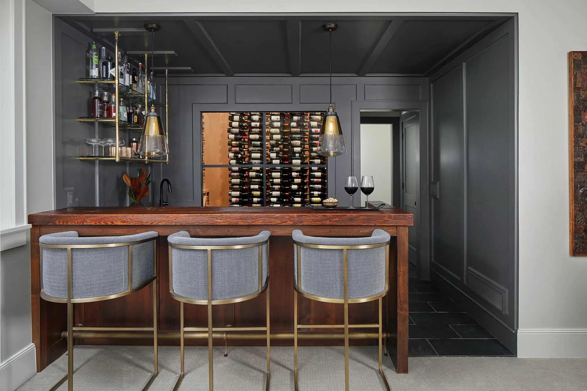 modern home bar with dark paneled walls, wood countertop, and a glass wine cellar display