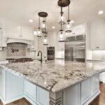 Luxurious kitchen featuring royal white granite countertops, white cabinetry, and modern pendant lighting.