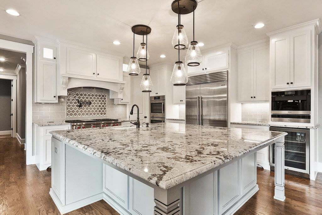 Luxurious kitchen featuring royal white granite countertops, white cabinetry, and modern pendant lighting.