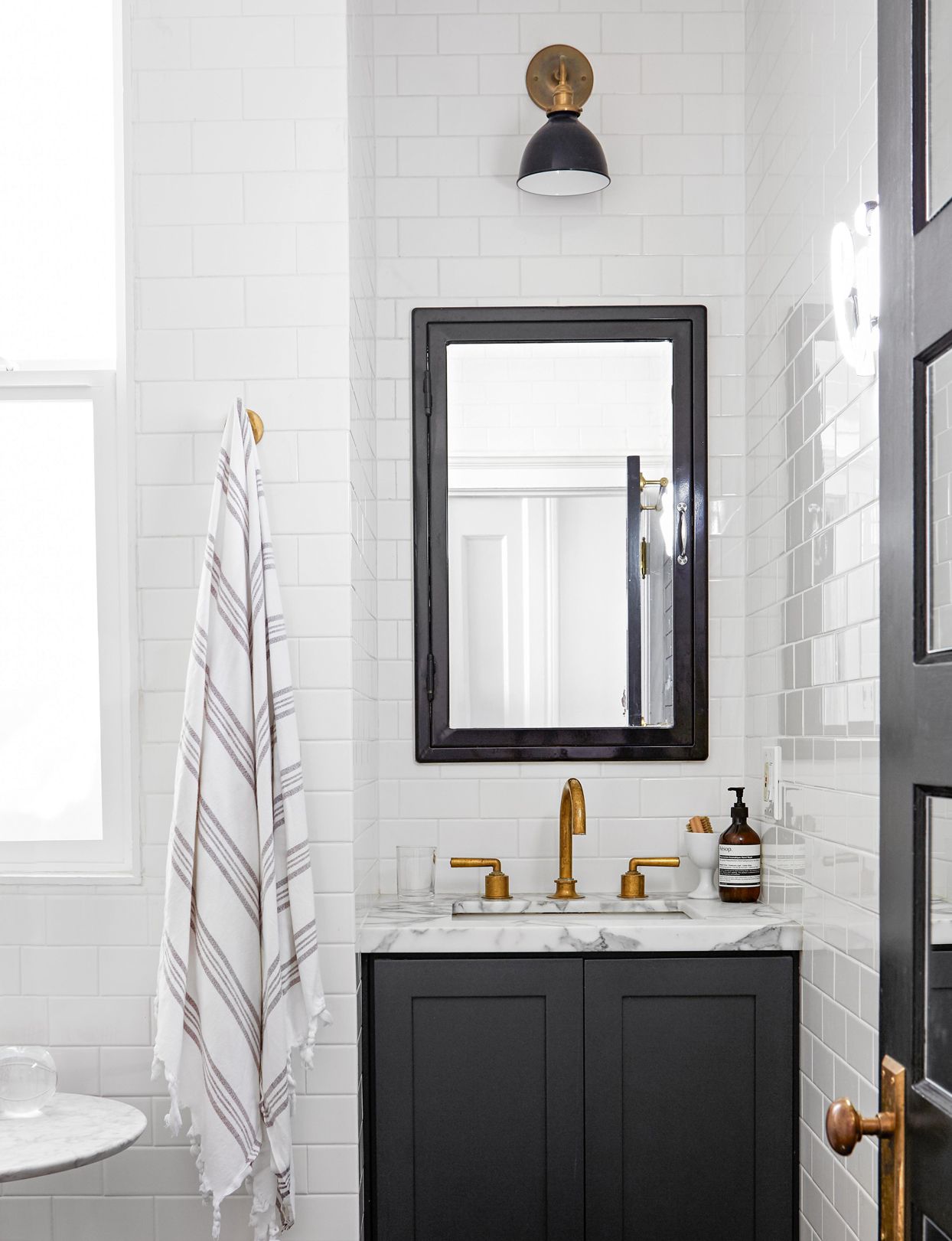 Modern black and white bathroom with brass fixtures and minimalist design.