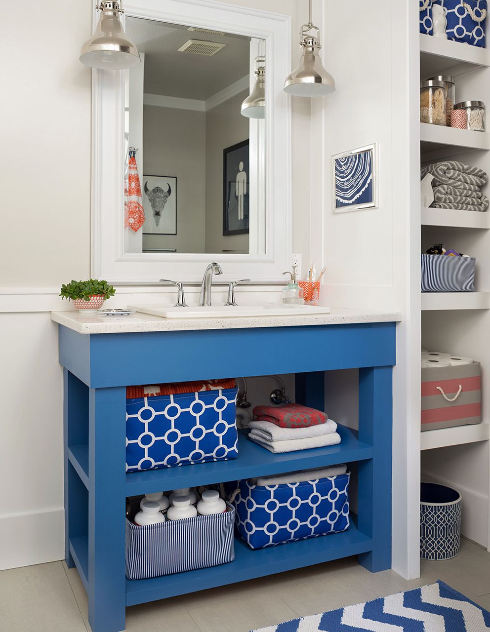 Bright bathroom with a blue vanity, modern faucet, and geometric storage baskets.