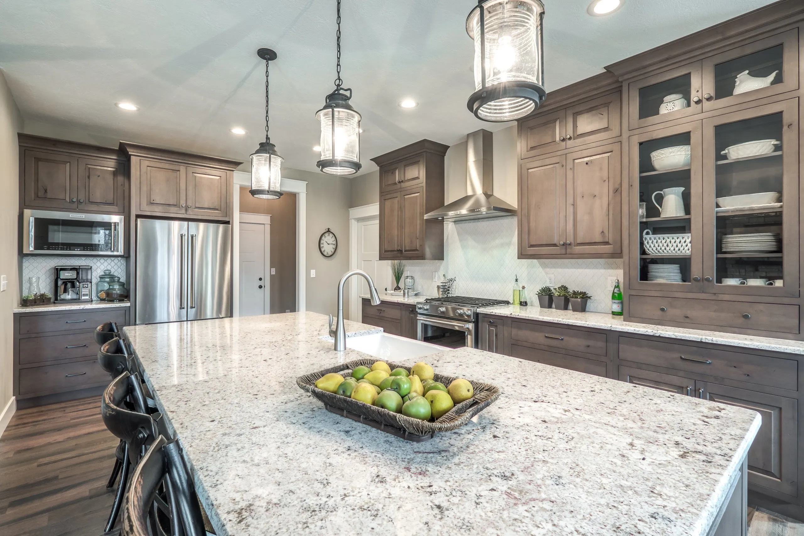 Rustic kitchen with knotty wood cabinets, stainless steel appliances, and a speckled granite island.