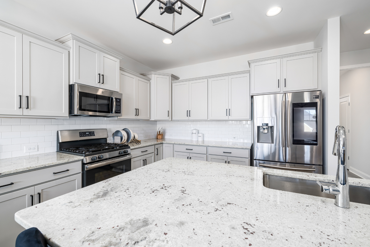 Modern kitchen with white granite countertops, gray shaker cabinets, and stainless steel appliances.
