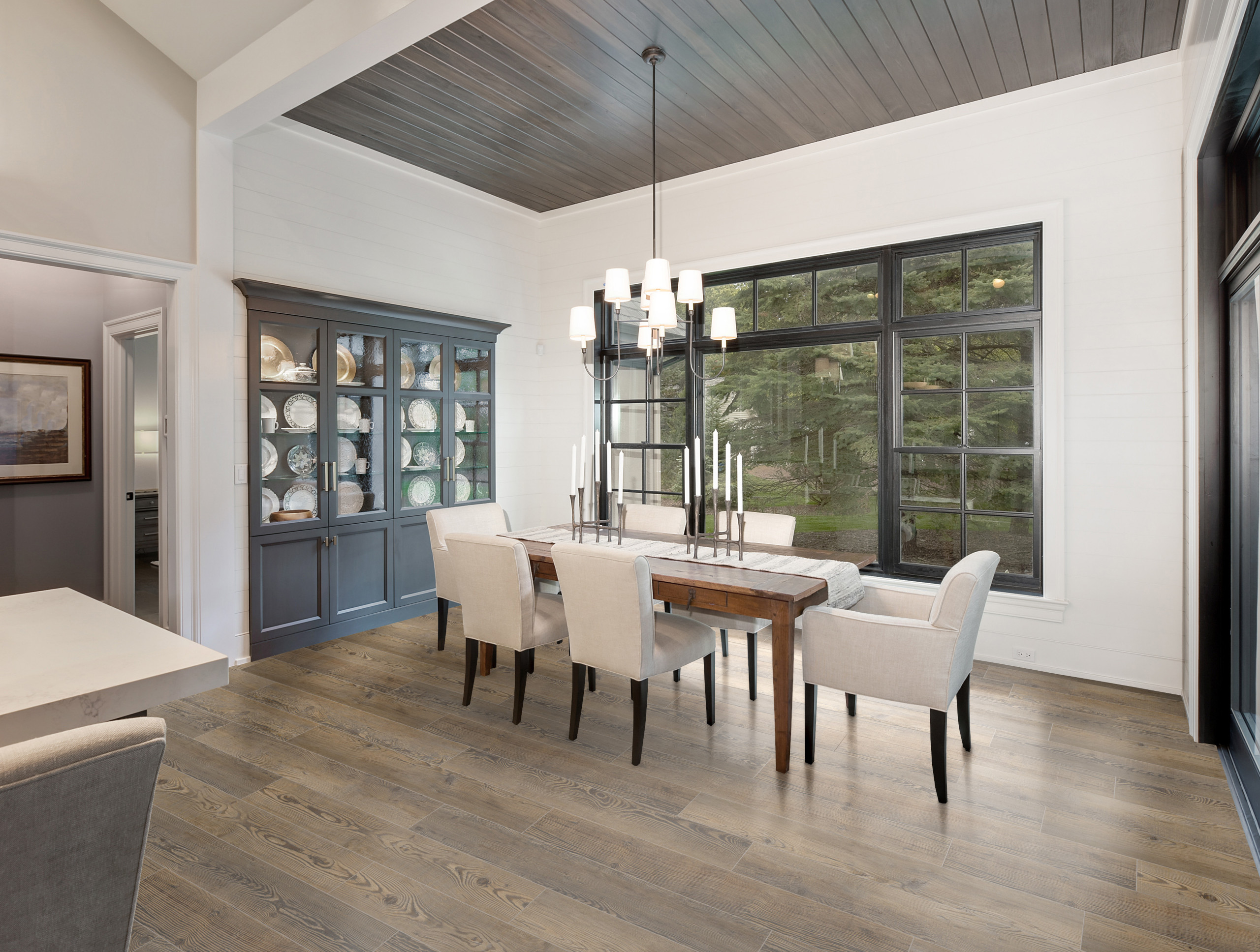Modern dining room with wooden table, upholstered chairs, and large windows