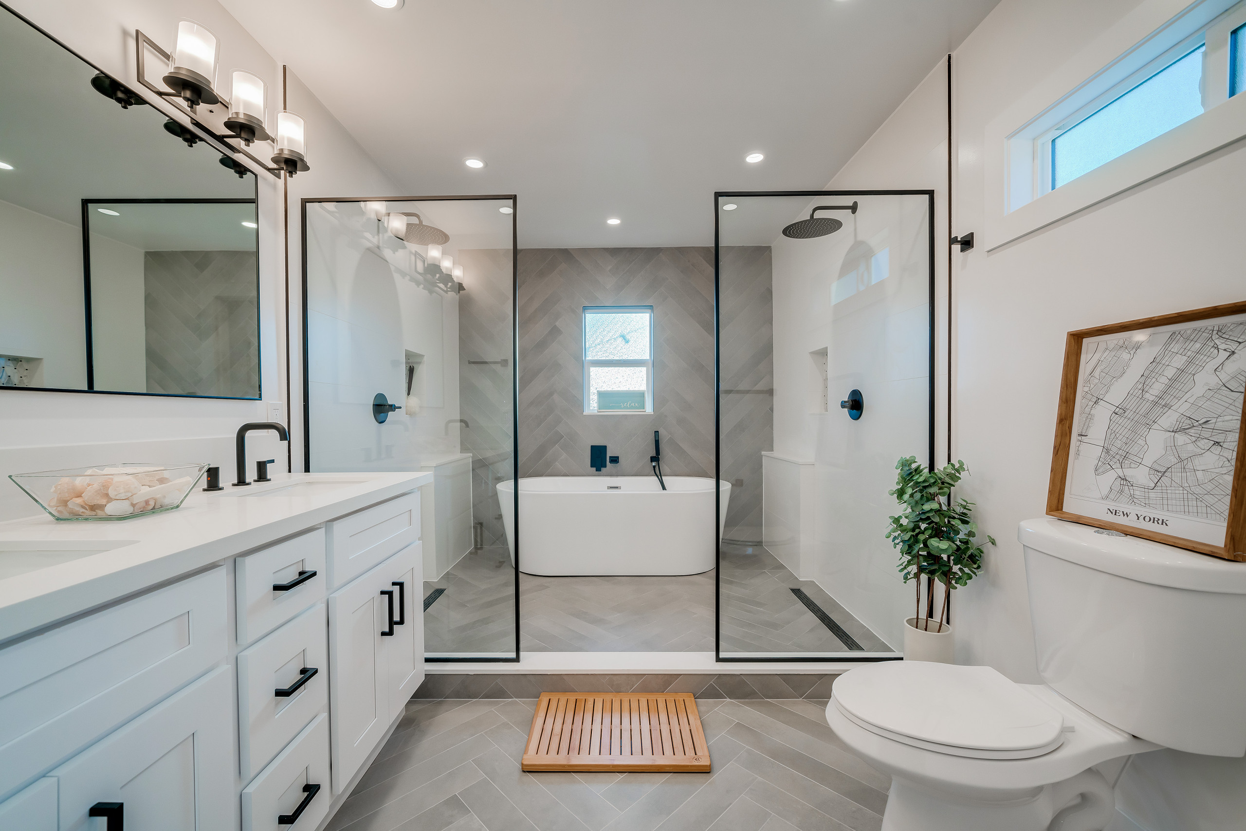 Modern bathroom with double vanity, freestanding tub, and glass shower enclosures