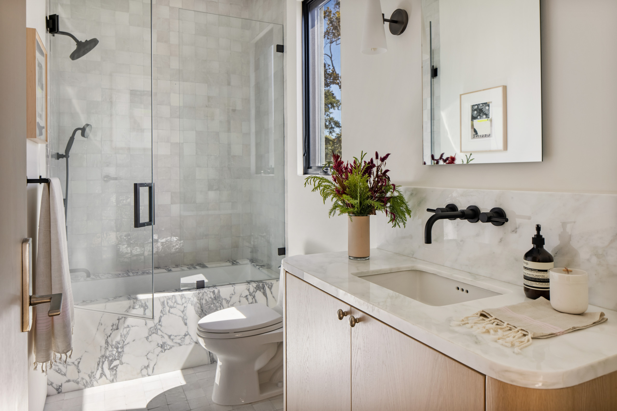 Modern bathroom with marble accents and glass shower.