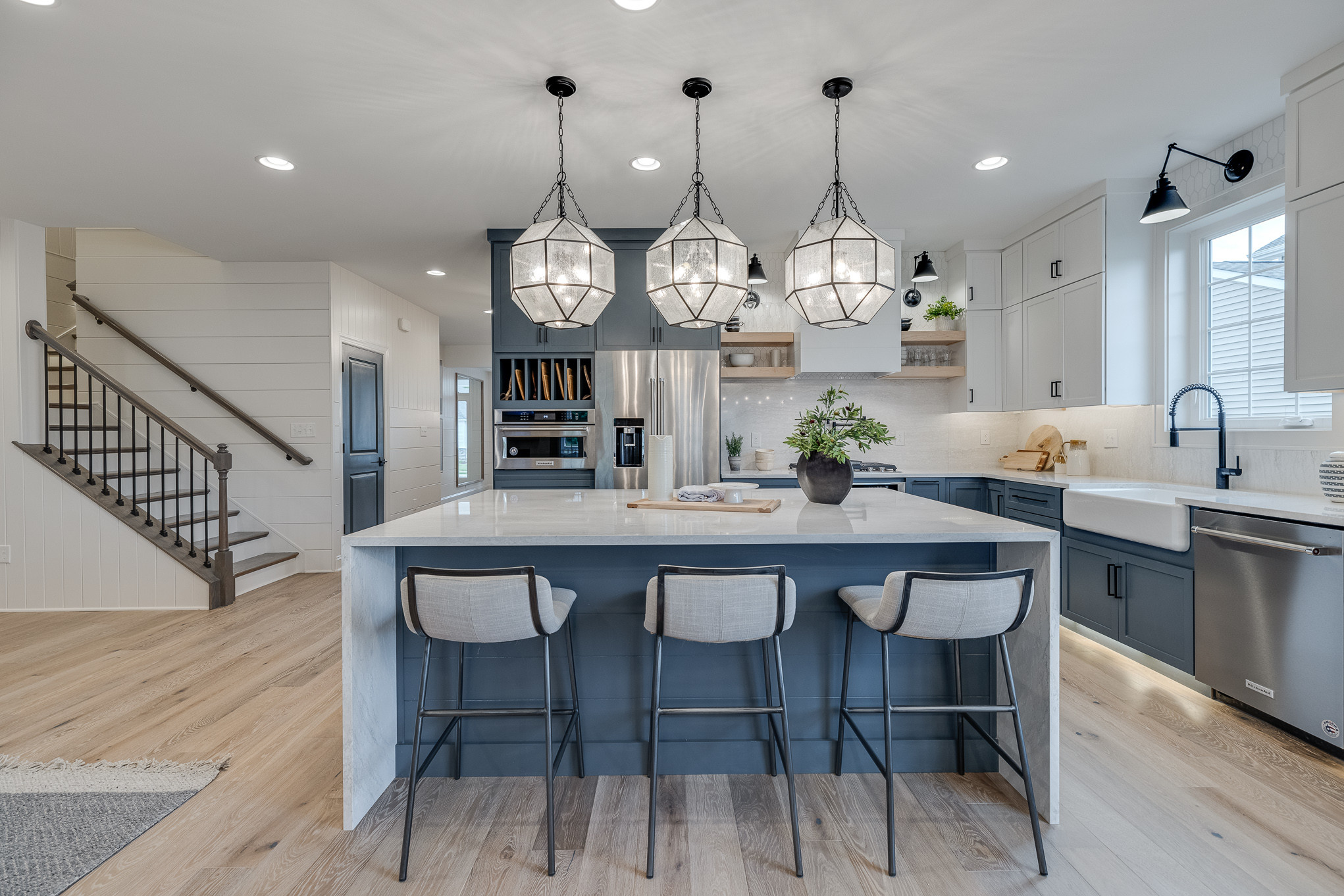 Modern kitchen with large island, pendant lighting, and navy blue cabinetry.