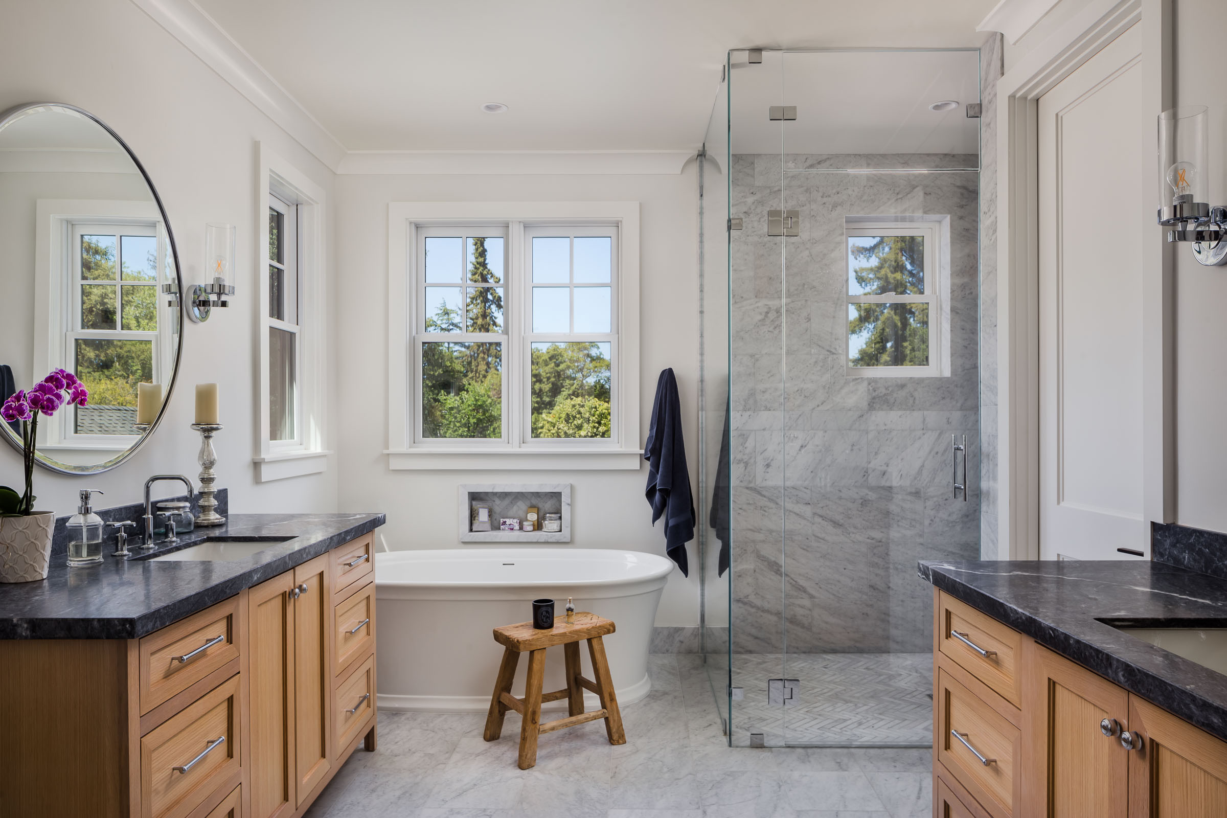 Luxury bathroom with wood vanities, freestanding tub, and glass shower