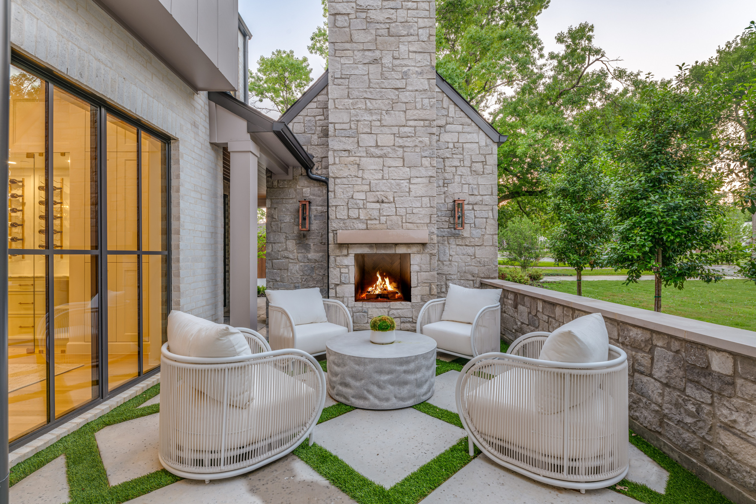 Outdoor patio with stone fireplace, modern white chairs, and round table
