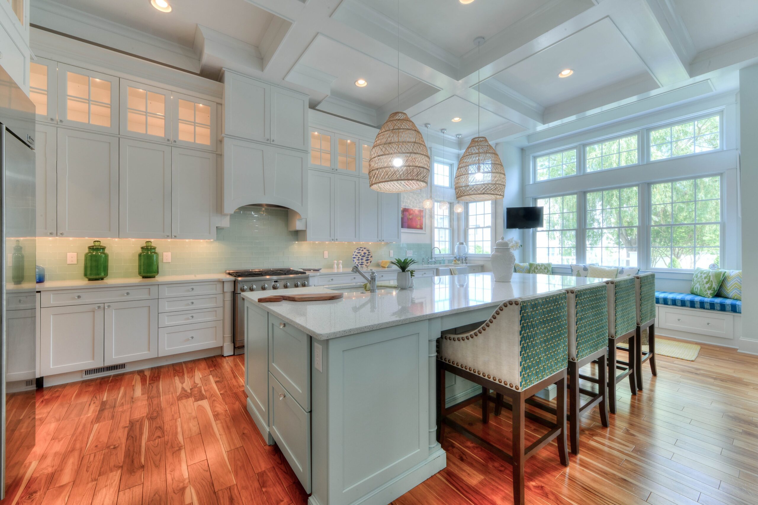 Bright and spacious modern kitchen with light blue cabinetry, natural wood flooring, and stylish pendant lighting