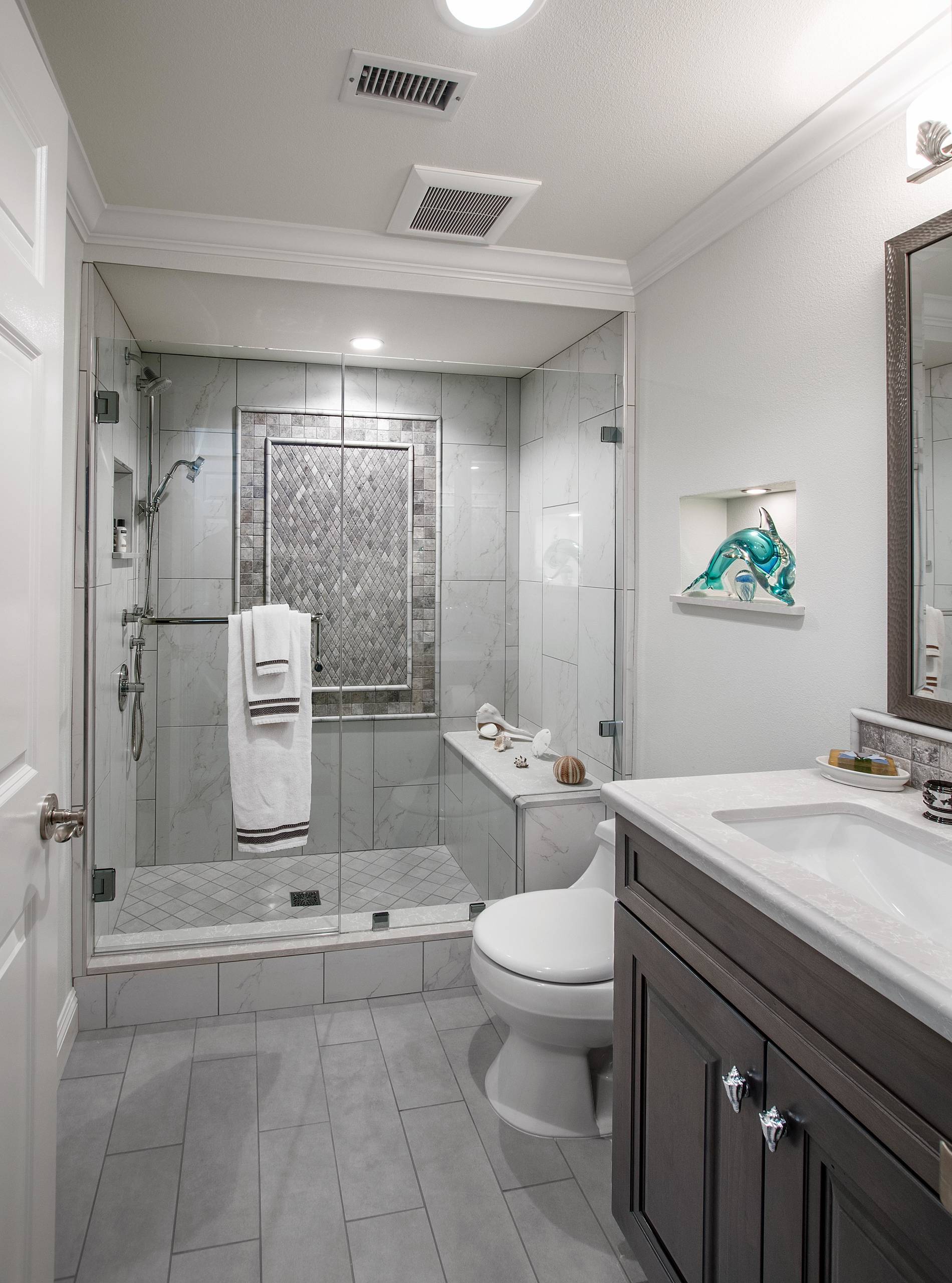 Compact bathroom with glass shower enclosure, gray tile accents, and vanity
