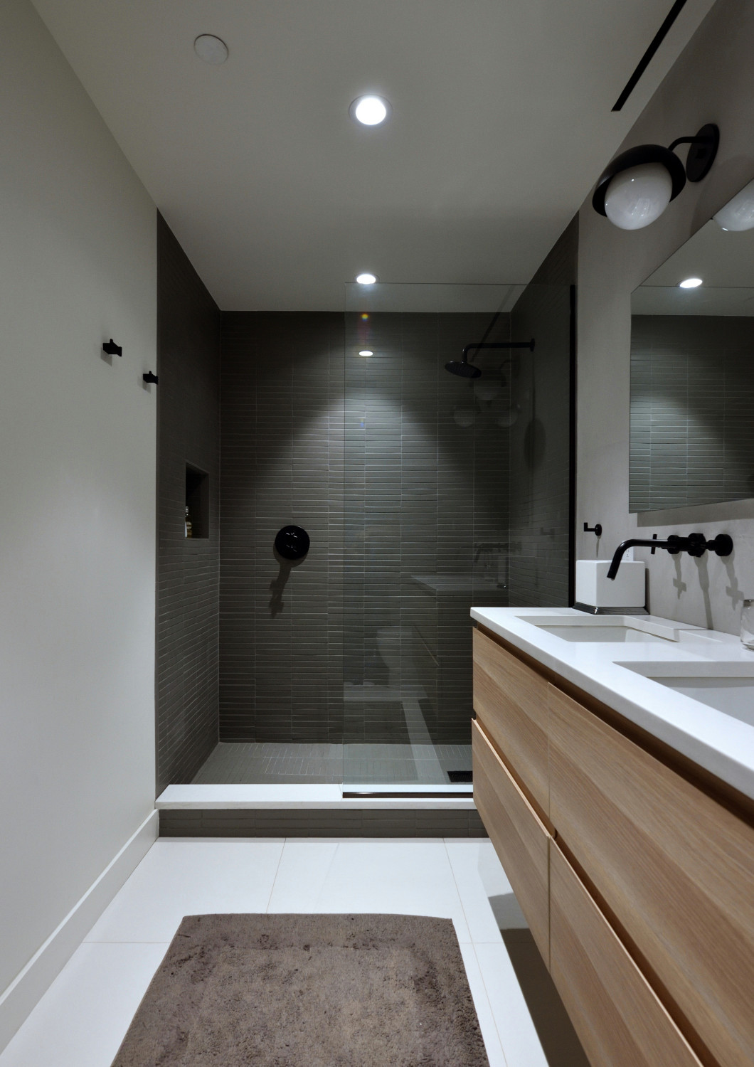 Modern bathroom with walk-in shower, floating wood vanity, and black fixtures