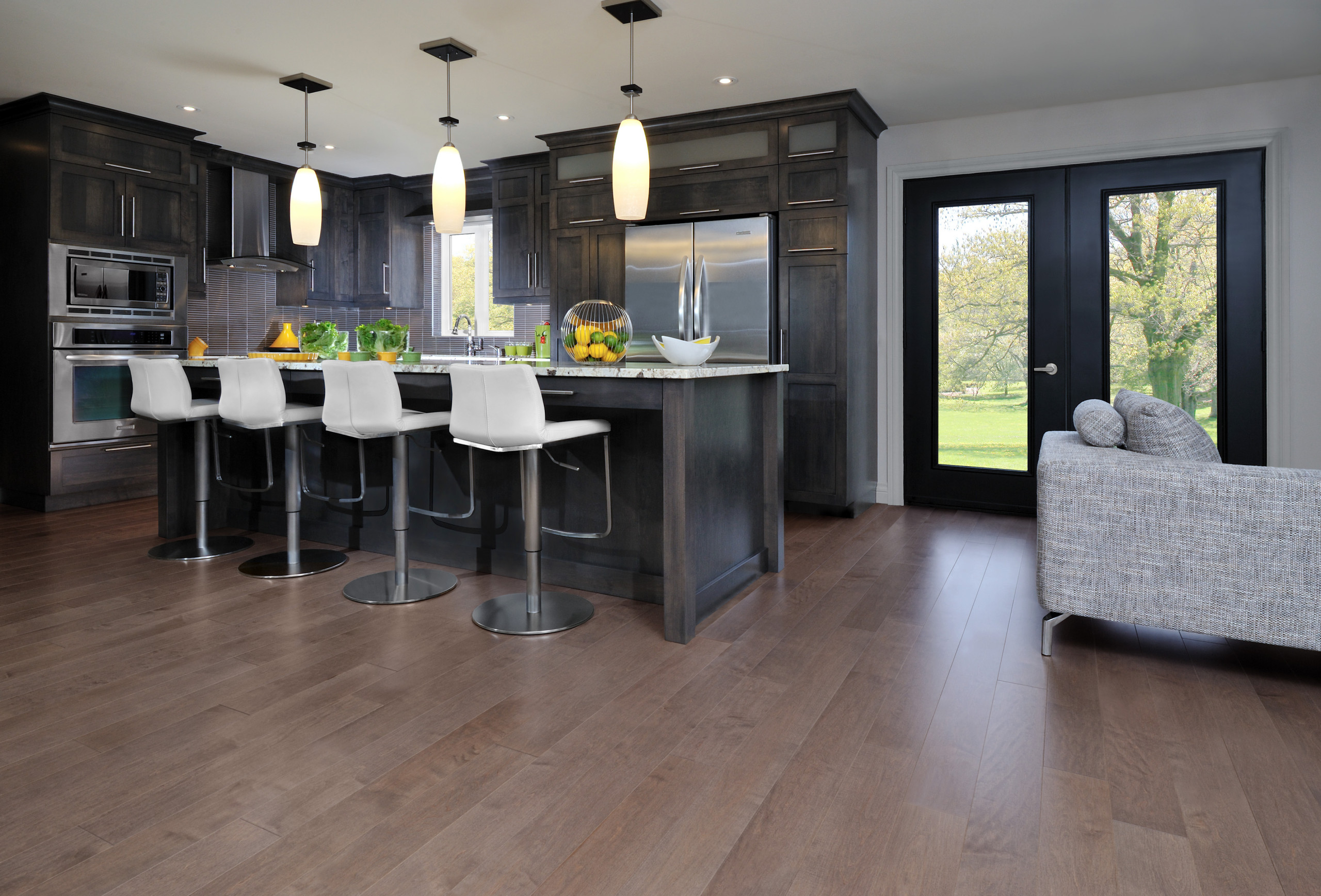 Modern kitchen with dark cabinets, white bar stools, and hardwood flooring