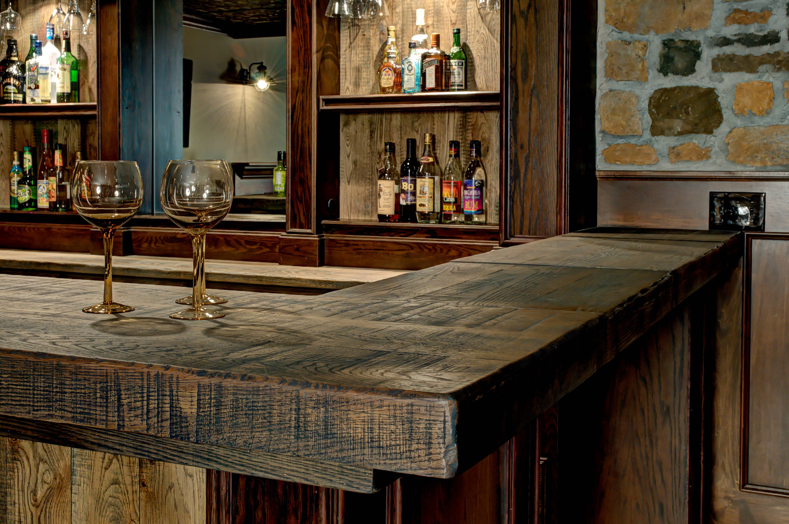 Rustic basement bar with reclaimed wood countertop and glassware.