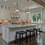 Traditional kitchen with white cabinets, large island, and pendant lighting.