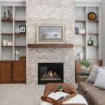 Modern living room with stone fireplace and wooden built-in shelves.
