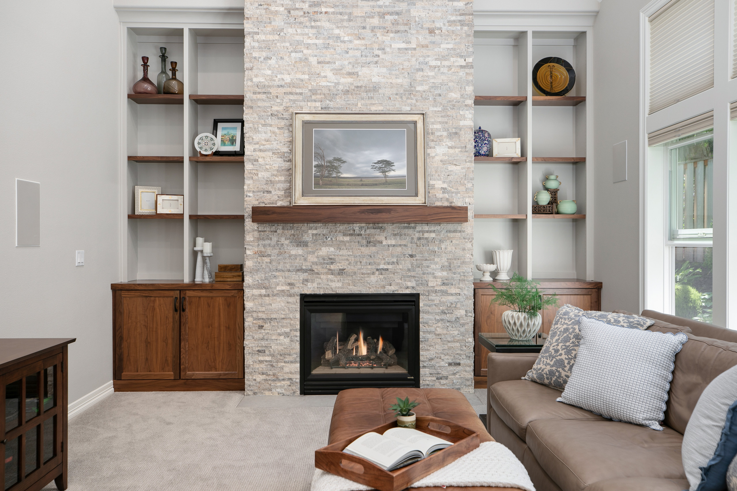Modern living room with stone fireplace and wooden built-in shelves.