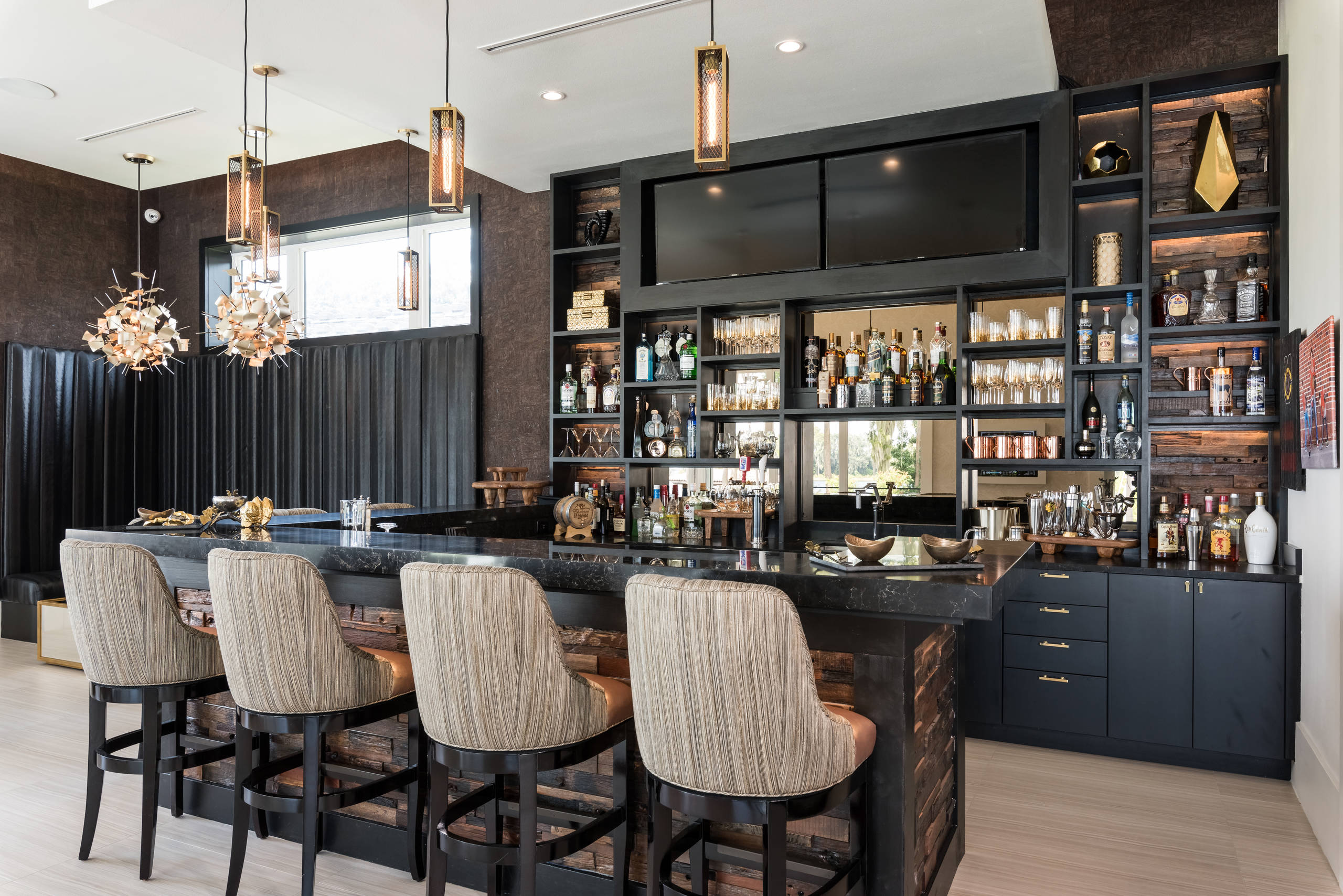 Luxury home bar with black cabinetry, backlit shelves, and modern pendant lighting.